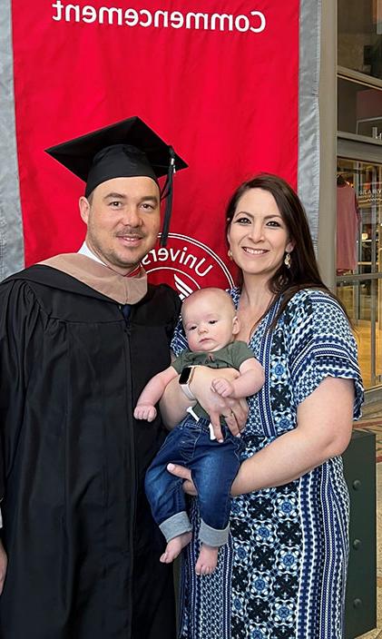 Jason Wells at commencement with his wife 和 son